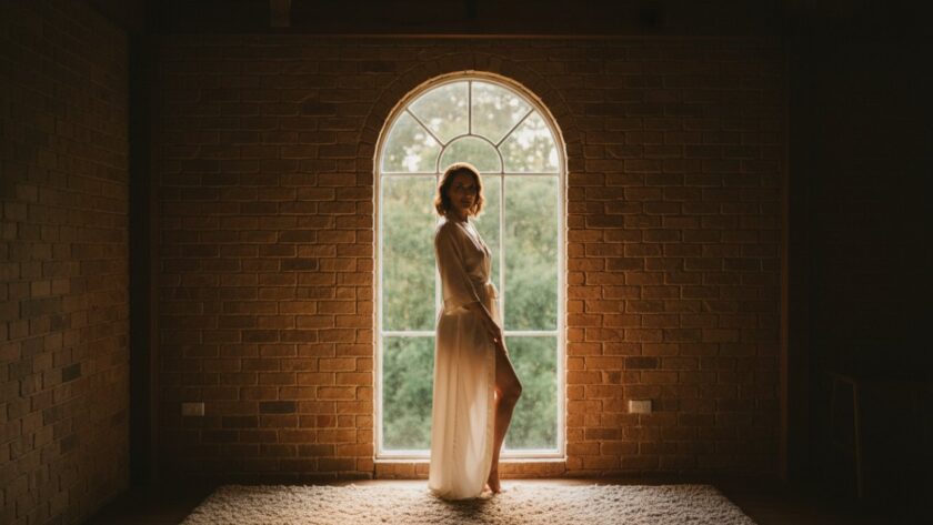 An empowering close-up portrait of a woman amidst the natural light of a rustic studio in Belgrave, Victoria, capturing her serene confidence during a Belgrave Victoria intimate boudoir photography experience, soft focus with warm tones, 'epic moment' style.