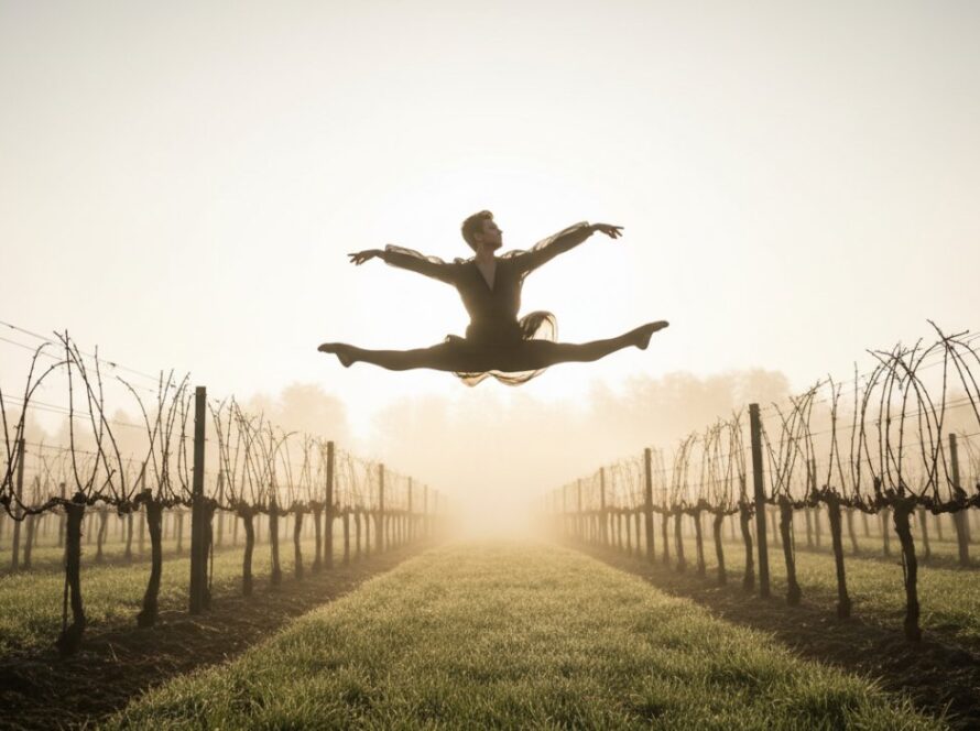 A prima ballerina mid-air, bathed in golden hour light, performing a breathtaking leap in a Coldstream vineyard, showcasing Coldstream ballet photography graceful poses in an epic moment of athletic artistry.