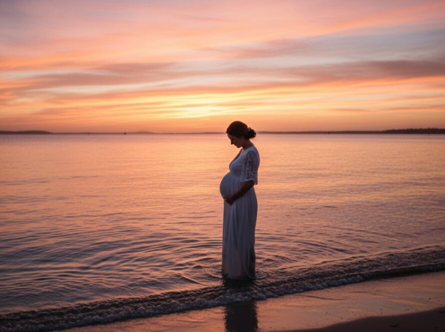 A glowing expectant mother embracing her bump during a dreamy Safety Beach maternity photo session at golden hour, silhouetted against a breathtaking coastal sunset with gentle waves on the shore, capturing an epic moment of serene beauty.