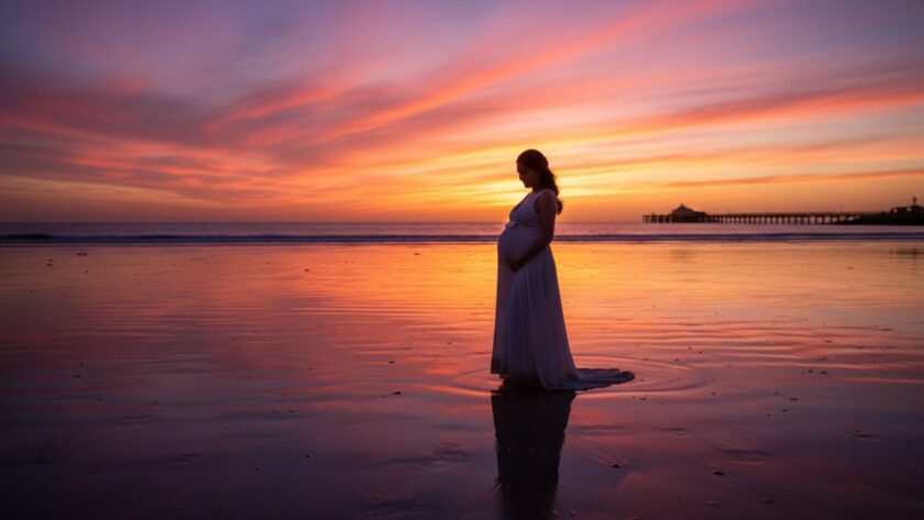 An expectant mother silhouetted against a vibrant Dromana Beach sunset, capturing the serene beauty of a Dromana Beach sunset maternity photography session, with waves gently lapping near the iconic Dromana Pier.