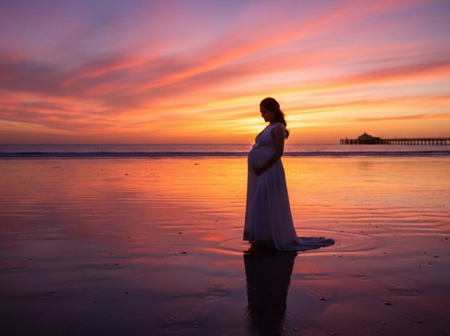 An expectant mother silhouetted against a vibrant Dromana Beach sunset, capturing the serene beauty of a Dromana Beach sunset maternity photography session, with waves gently lapping near the iconic Dromana Pier.