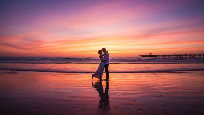 An epic moment of a couple embracing on Dromana beach at sunset, silhouetted against a vibrant orange and purple sky, showcasing Dromana engagement photography beach sunset.