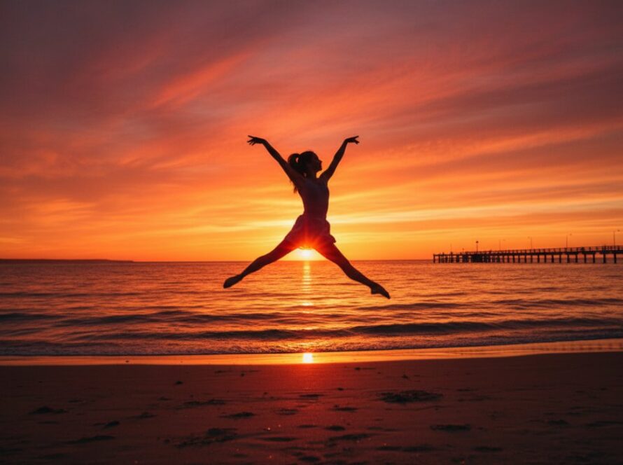 A ballet dancer striking an elegant, powerful pose mid-air during a dynamic dance photography Tootgarook beach sunset session, with the golden hour light illuminating their silhouette against the calm waters of Port Phillip Bay and the iconic Tootgarook pier in the distance, capturing an epic moment of grace and strength.