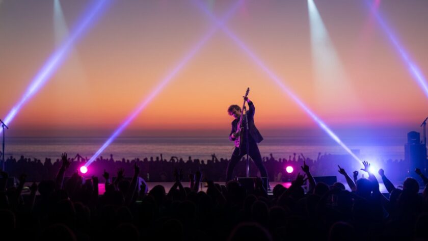 Dynamic shot of a musician on stage, bathed in colourful lights, capturing the Portsea foreshore live music photography vibrant energy during a memorable concert in Portsea, Victoria.