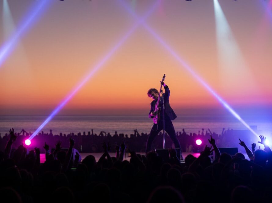 Dynamic shot of a musician on stage, bathed in colourful lights, capturing the Portsea foreshore live music photography vibrant energy during a memorable concert in Portsea, Victoria.