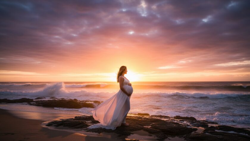 An expectant mother, bathed in the soft, golden light of sunset at Rye Beach, Victoria, during her Rye Victoria pregnancy glow photoshoot stunning beach backdrops. She cradles her baby bump against a dramatic ocean backdrop, waves gently lapping near her feet, capturing a serene and powerful moment.