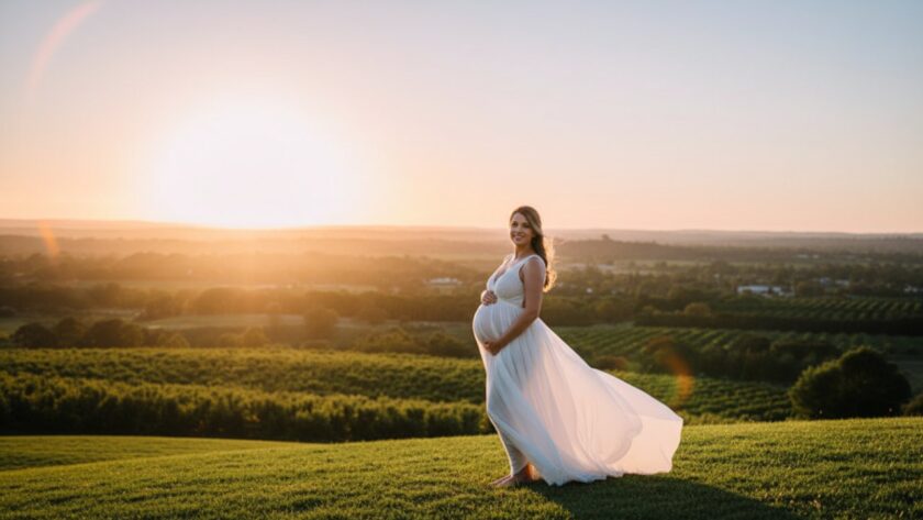 A glowing pregnant woman in a flowing white dress, silhouetted against a golden Wandin East sunset, holding her belly, capturing serene outdoor maternity photos Wandin East with an ethereal glow.