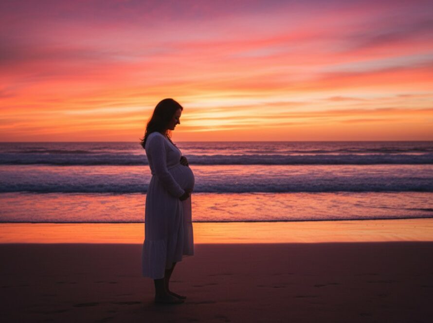 A glowing expectant mother stands silhouetted against a dramatic sunset on Somers beach, Victoria, during her Somers beach maternity photoshoot Victoria, capturing an epic, ethereal moment with the ocean waves gently lapping at her feet and the sky painted in fiery oranges and purples.