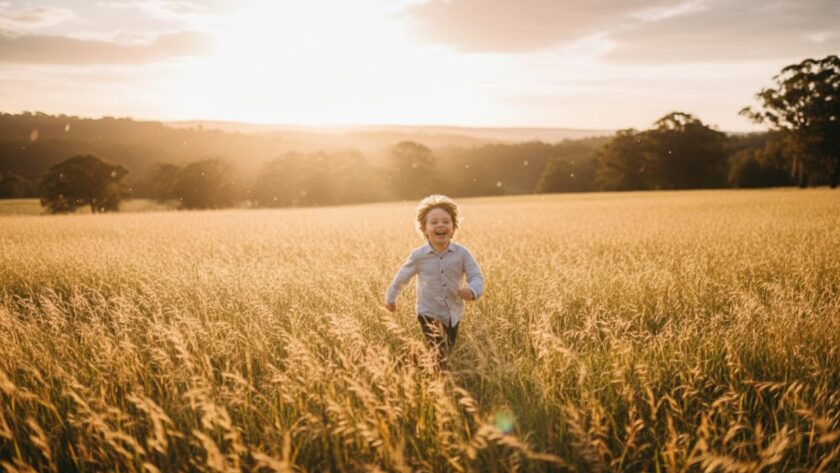 A vibrant Steels Creek kids photography natural light scene showing a young child laughing joyfully amidst sun-dappled trees at sunset, captured in an epic, emotive moment.