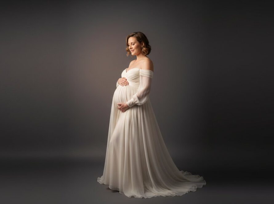 A serene and elegant portrait featuring a radiant pregnant woman in a flowing gown, bathed in soft studio light, embodying the timeless Safety Beach studio maternity photography experience.