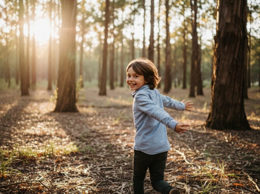 An epic moment captured in Upwey family photography candid children moments: A young child with a wide, joyful smile, running through a sun-dappled eucalyptus forest in Upwey, dappled golden light creating lens flares, a sense of wild freedom and pure happiness, blurred autumn leaves in the foreground, close-up, dynamic shot, natural colours.