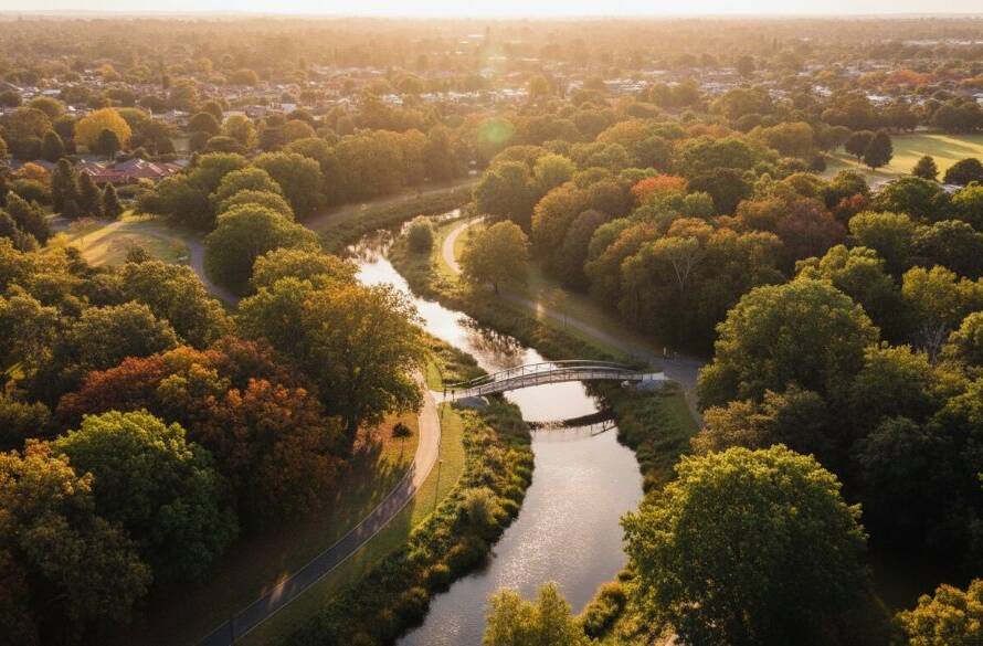 A stunning Ashwood VIC aerial landscape drone photography shot captures a golden hour over Gardiner's Creek Trail, showing the lush canopy and winding path from an elevated perspective, bathed in warm, dramatic light, conveying a sense of serene beauty and vastness.