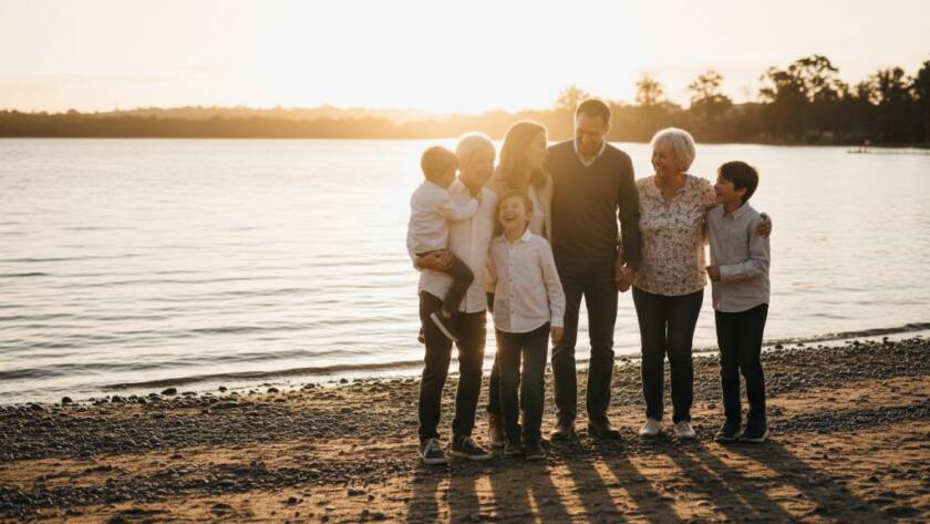 An authentic candid family photography Manor Lakes moment, showcasing a family laughing joyously by the lakeside at sunset, capturing genuine connection with warm, dramatic lighting and professional colour grading.