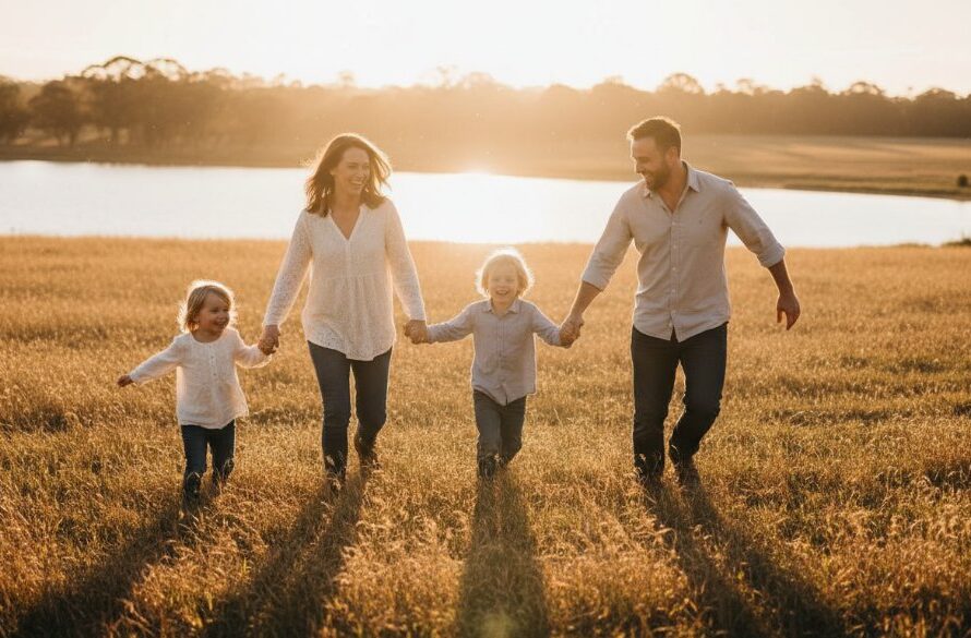A heartwarming, genuine moment of a Newborough family laughing joyfully during an outdoor picnic, captured with authentic candid family photography Newborough, featuring natural light filtering through gum trees at Lake Narracan, embodying unposed happiness.
