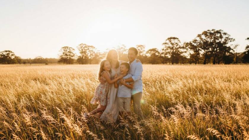 An epic moment capturing a family laughing joyfully during their authentic family photos Cranbourne West moments session, with warm evening light silhouetting them against a natural Cranbourne West parkland setting, showcasing genuine connection and happiness.