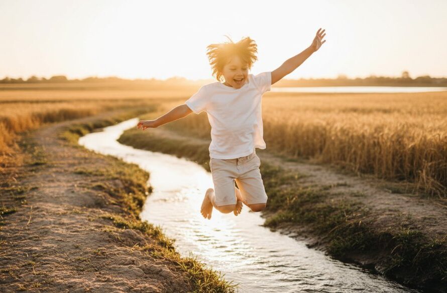 An emotionally resonant, wide-angle 'epic moment' photograph capturing authentic kids photography Horsham Victoria: a young child, mid-laugh, running through a sun-drenched field of golden wheat at sunset, with the Wimmera River in the background. The child's arms are outstretched, joyfully engaging with the environment, bathed in warm, dramatic golden hour light. Professional color grading enhances the magical, fleeting moment of childhood.
