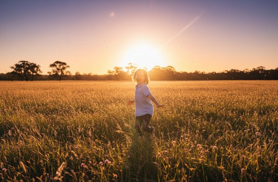 An epic, sun-drenched photograph capturing authentic kids photography moments Sale, featuring a child joyfully running through a sun-kissed field near Sale Common, with dramatic golden hour lighting and a wide, genuine smile.