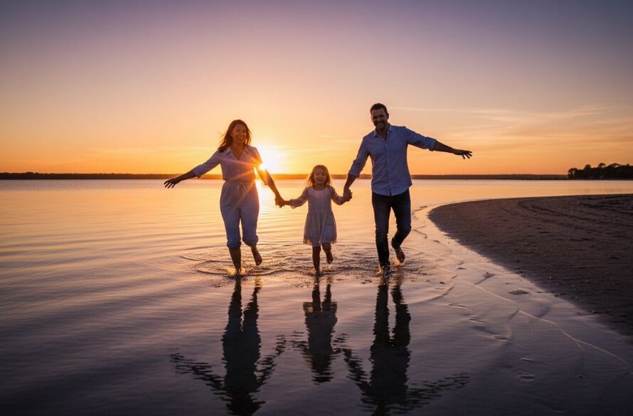 A heartwarming, epic candid shot of a family laughing joyfully by the shimmering waters of Lakes Entrance at sunset, beautifully illustrating authentic Lakes Entrance candid family photography storytelling.