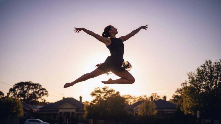 Dynamic, low-angle Balwyn dance photography capturing movement and emotion, featuring a female ballet dancer mid-air in an epic, powerful leap against the golden hour light near Balwyn Park, showcasing strength and grace.