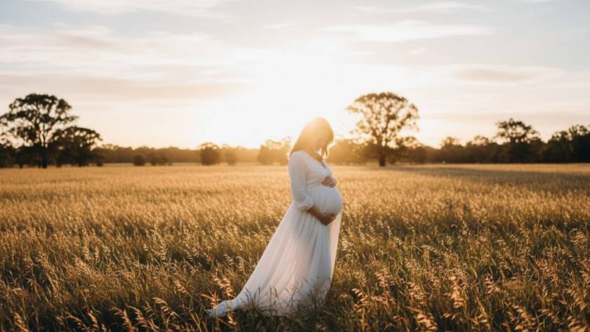 A glowing pregnant woman in a flowing gown, silhouetted against a golden sunset in a lush Bentleigh East park, during her bentleigh east outdoor maternity photography session, embodying serene anticipation.