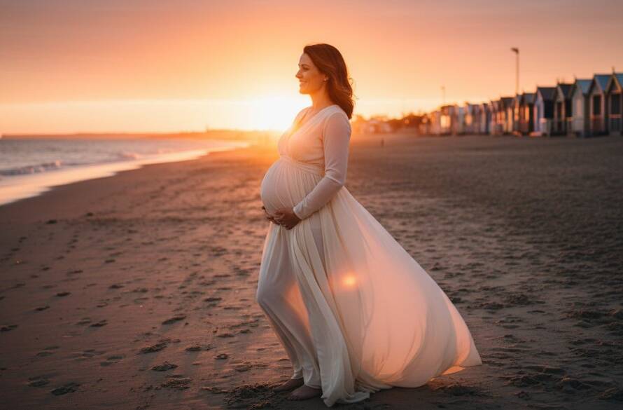 An expectant mother, silhouetted against a golden sunset at Brighton Beach, radiating joy during her Brighton Beach glowing maternity portraits, with the iconic bathing boxes in the soft background.