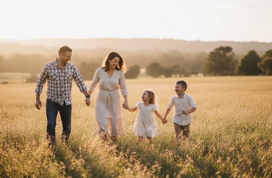 An epic moment of a family laughing joyfully amidst the golden hour light in a scenic park in Churchill, Victoria, showcasing authentic family photography Churchill Victoria scenic parks, with children playing and parents embracing.