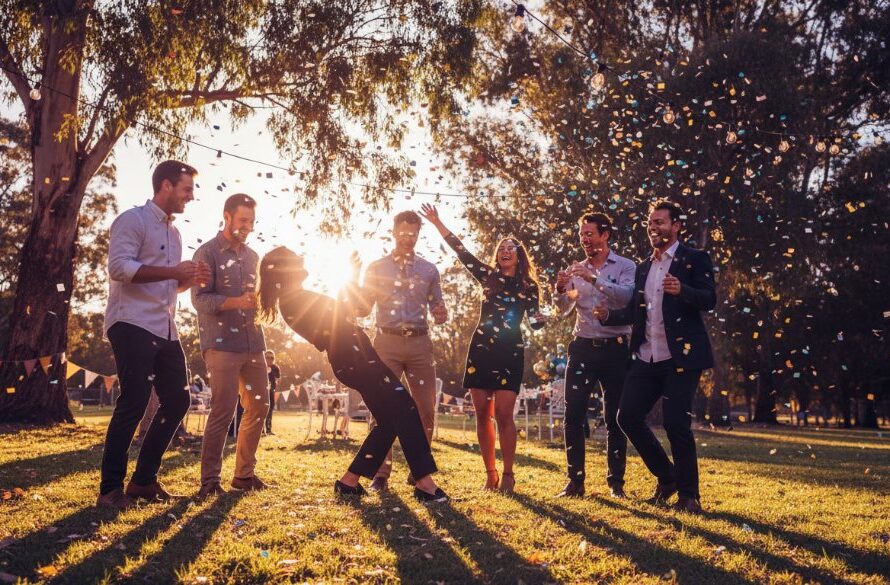 An epic moment of pure joy captured through candid party photos in South Geelong Victoria, showing guests laughing and dancing under string lights at a vibrant outdoor celebration, professional photography with dramatic backlighting.