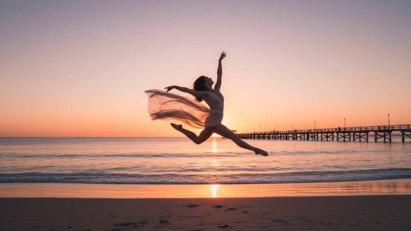 A dramatic wide shot of a contemporary dancer performing an elegant, powerful leap against the golden hour sunset at Seaford Pier, Victoria, embodying 'captivating dance photography Seaford pier Victoria', with the ocean and pier in the background, showcasing dynamic movement and emotional intensity.