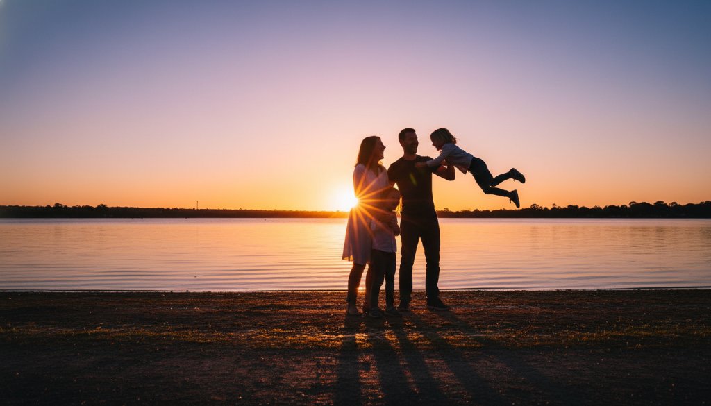 A stunning candid photograph 'Capturing candid family joy Maryborough Victoria', showing a family laughing heartily on a golden-lit afternoon near Lake Victoria in Maryborough, silhouetted slightly with warm, cinematic tones.