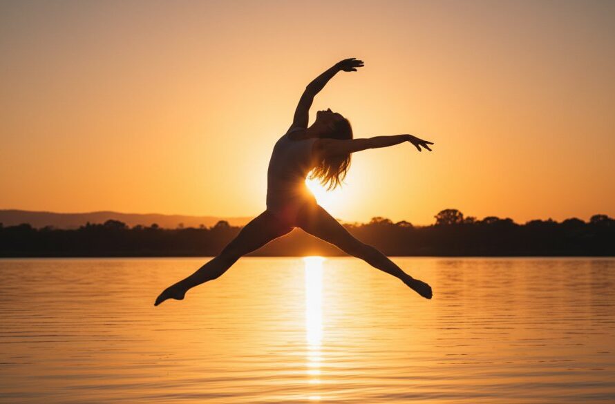 An energetic dancer mid-leap, silhouetted against a dramatic sunset over Lake Narracan, perfectly illustrating dynamic dance photography moments in Moe Victoria, captured with professional lighting.