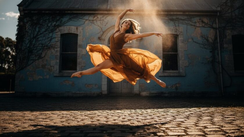 A female contemporary dancer captured mid-leap with incredible grace and power over a cobblestone path against a weathered Sebastopol bluestone building, showcasing the dynamic artistry of Capturing dynamic dance photography Sebastopol Victoria. Dramatic golden hour light emphasizes her form and the historic setting, creating an epic, professional portfolio shot.
