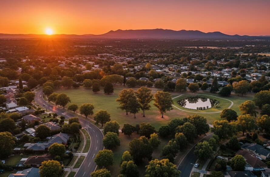 A dramatic aerial shot capturing Forest Hill's beauty with drone photography, showcasing golden hour light illuminating the leafy residential streets, a serene park, and distant Dandenong Ranges under a vibrant sunset sky, professionally color-graded.