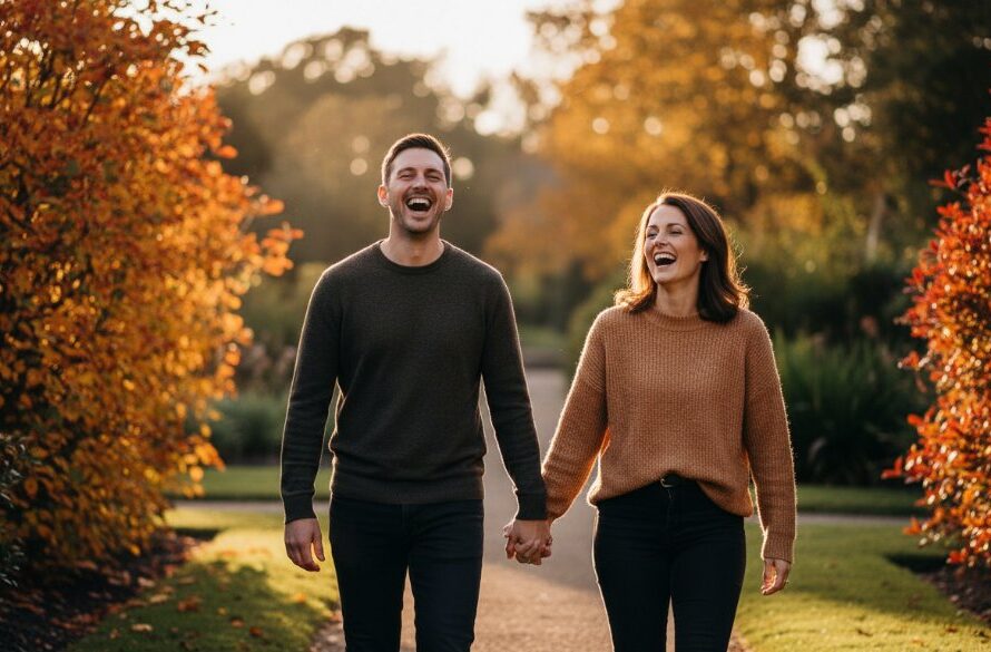 An epic, emotionally charged photograph showcasing Castlemaine candid photography capturing genuine moments Victoria, featuring a couple laughing spontaneously under dramatic golden hour light, near the historic Castlemaine Botanic Gardens, with vibrant autumn colours, expertly composed for a cinematic feel.