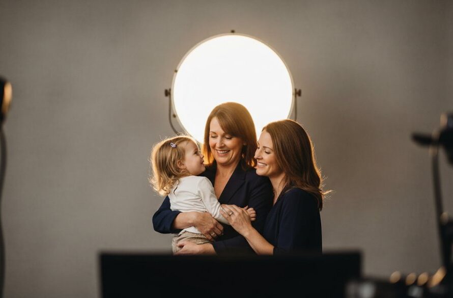 An emotionally resonant, wide-angle, professional photograph showcasing a family of three (parents and a young child) bathed in soft, warm studio light, laughing genuinely. The focus is on their joyous connection, captured in a Colac boutique studio photography for timeless portraits session, with a subtle, elegant backdrop and cinematic colour grading.