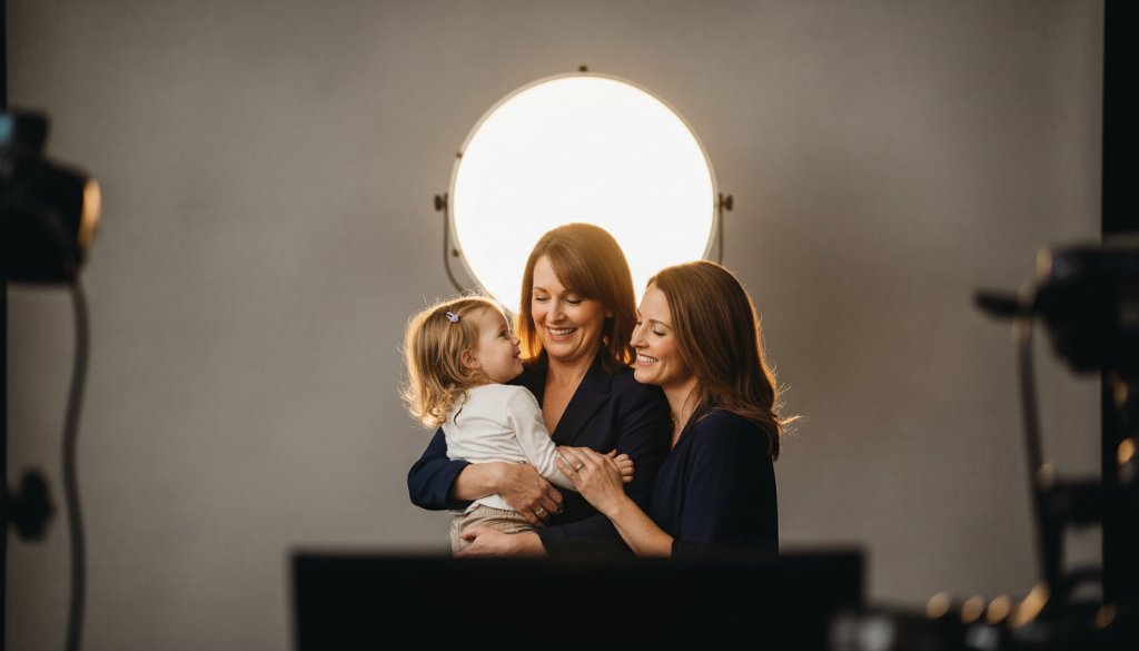 An emotionally resonant, wide-angle, professional photograph showcasing a family of three (parents and a young child) bathed in soft, warm studio light, laughing genuinely. The focus is on their joyous connection, captured in a Colac boutique studio photography for timeless portraits session, with a subtle, elegant backdrop and cinematic colour grading.