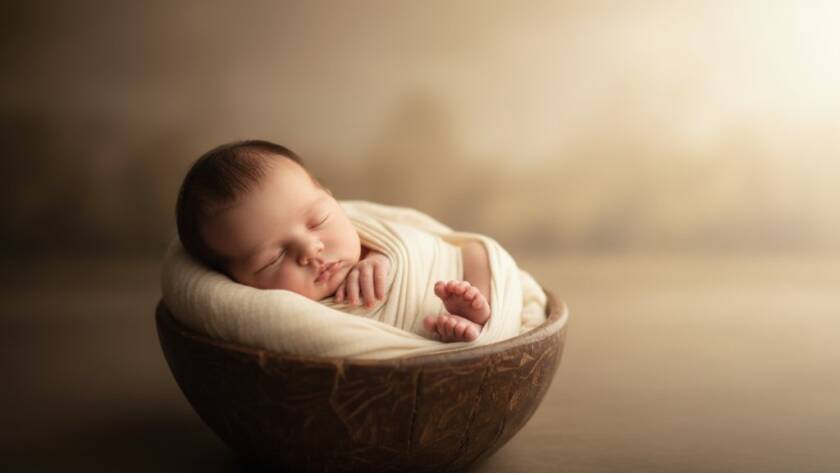 An intimate, heartwarming 'epic moment' photograph showcasing a newborn baby in a soft, ethereal wrap, gently cradled in their parent's hands, bathed in golden hour light within a rustic, natural setting near Cranbourne South, Victoria, embodying Cranbourne South newborn photography precious moments.