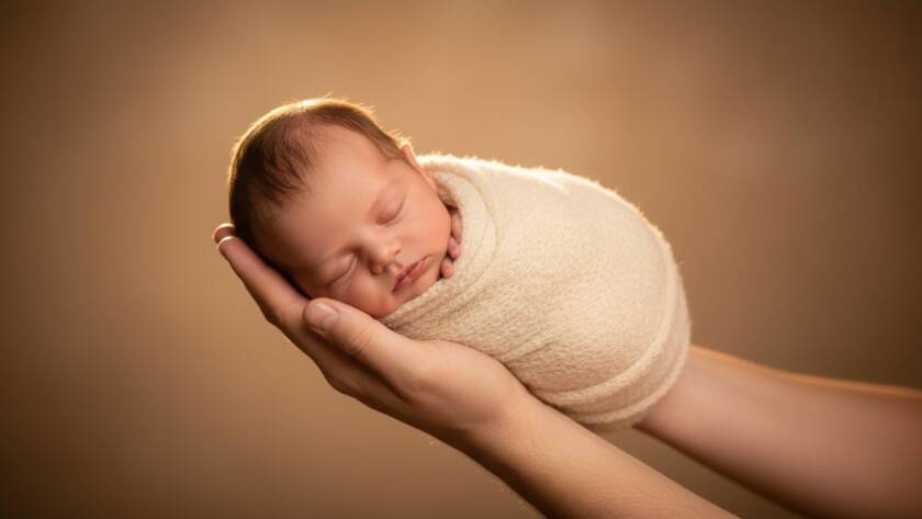 A heartwarming, professional portrait capturing a tiny baby nestled peacefully in soft wraps, surrounded by gentle, natural light in a warm studio setting in Croydon North, representing expert newborn photography preserving early moments.