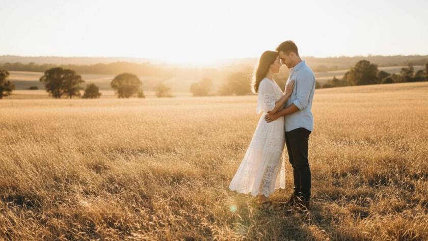 A couple embraces tenderly at sunset amidst golden fields and rustic fences in Derrimut, Victoria, beautifully capturing the essence of Derrimut Victoria Rustic Pre-Wedding Photography with dramatic, cinematic lighting.