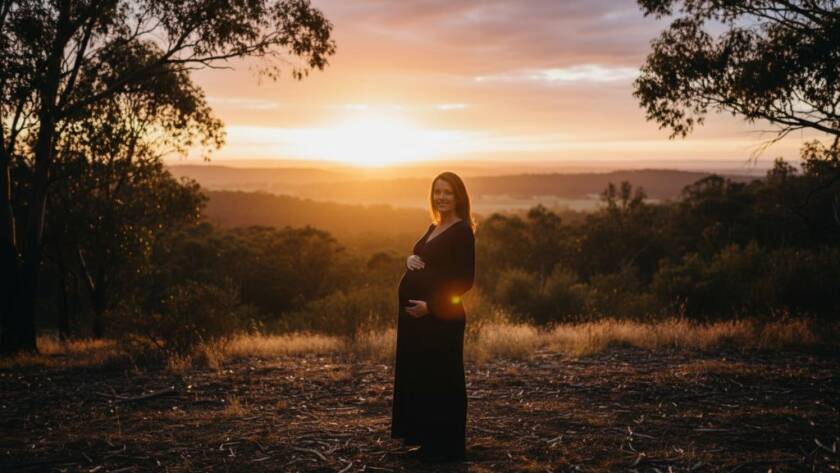 An expectant mother, radiating joy, stands gracefully amidst the golden hour glow of a natural bushland setting in Donvale, Victoria, during her Donvale maternity photoshoot serene natural light session, captured with professional cinematic lighting and warm colour grading.
