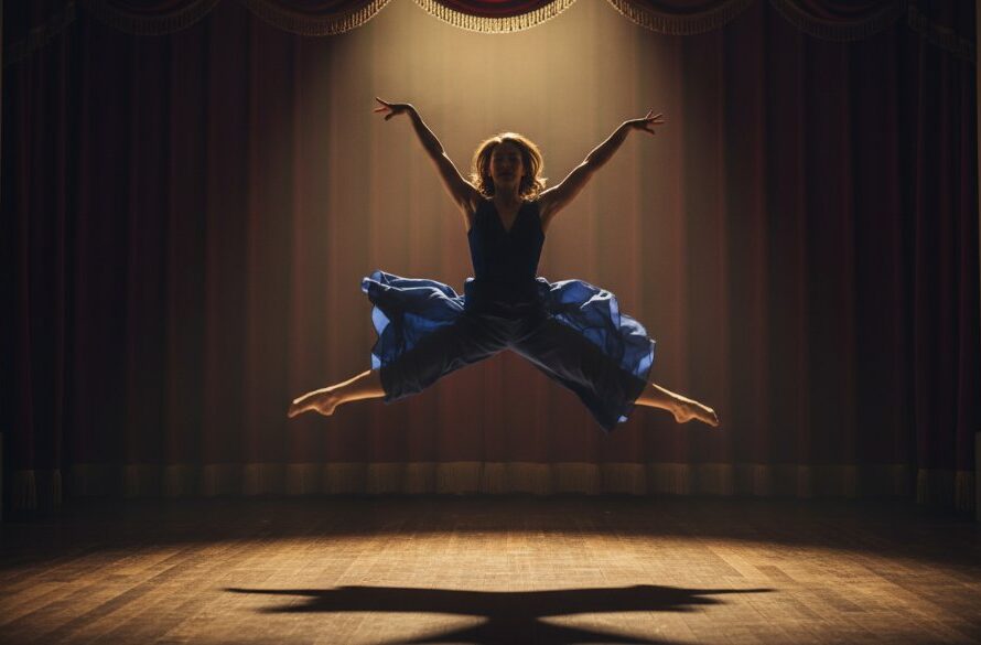 An epic moment of a dancer mid-air, bathed in dramatic stage lighting, performing a powerful leap against a blurred backdrop, embodying the dynamic Bairnsdale dance photography spirit and grace.