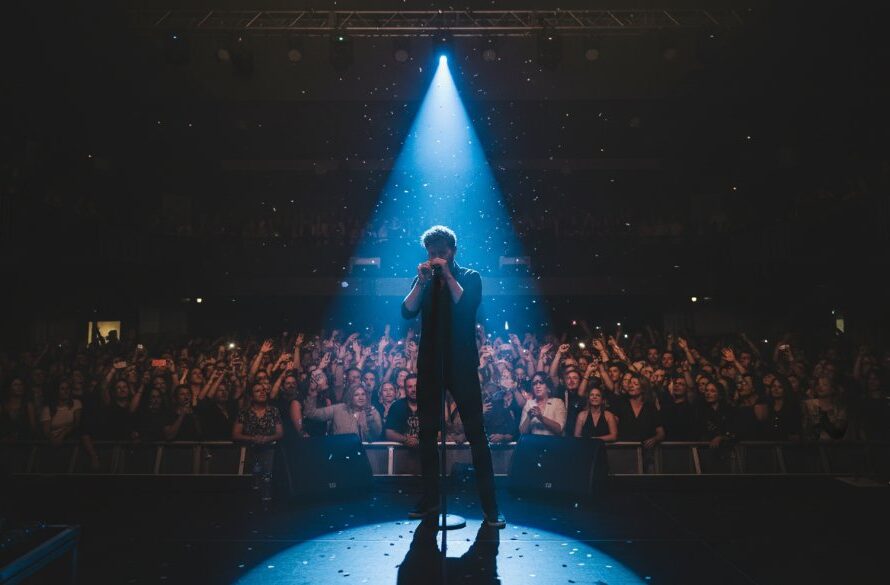 A wide-angle, dramatic shot of a lead guitarist mid-shred under intense stage lights at a vibrant Mount Clear music venue, capturing the immense dynamic concert photography Mount Clear musical energy, with the crowd visible as a blur of adoration in the foreground.
