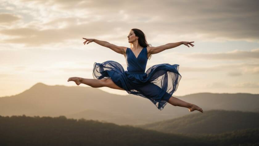 A stunning, low-angle shot capturing the dynamic dance photography artistry of a female dancer mid-air, silhouetted against a dramatic sunset over the Dandenong Ranges near Upper Ferntree Gully, showcasing incredible strength and grace with professional lighting.