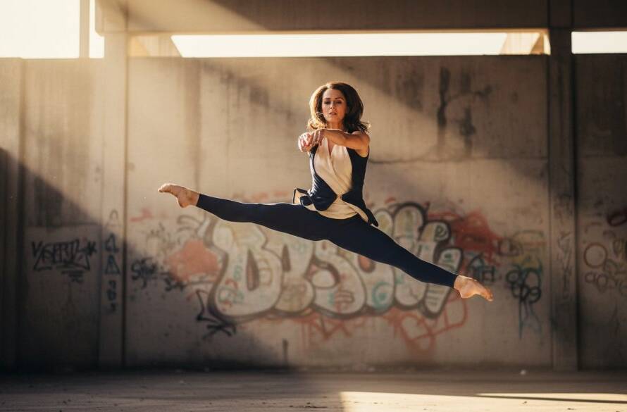 Dynamic dance photography Clyde North capturing passion in an epic moment of a dancer mid-leap against a dramatic, moody urban backdrop, showcasing power and grace with professional studio lighting.