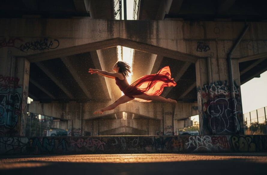 An elegant dancer mid-air, bathed in dramatic theatrical lighting, performing an exquisite leap in a studio setting, showcasing dynamic dance photography Noble Park Victoria with exceptional clarity and emotion.