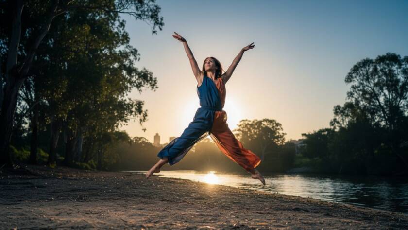 A ballet dancer mid-air, silhouetted against a dramatic sunset over the Yarra River near Templestowe Lower, showcasing dynamic dance photography in Templestowe Lower Victoria with professional studio lighting effects and rich, cinematic colour grading.