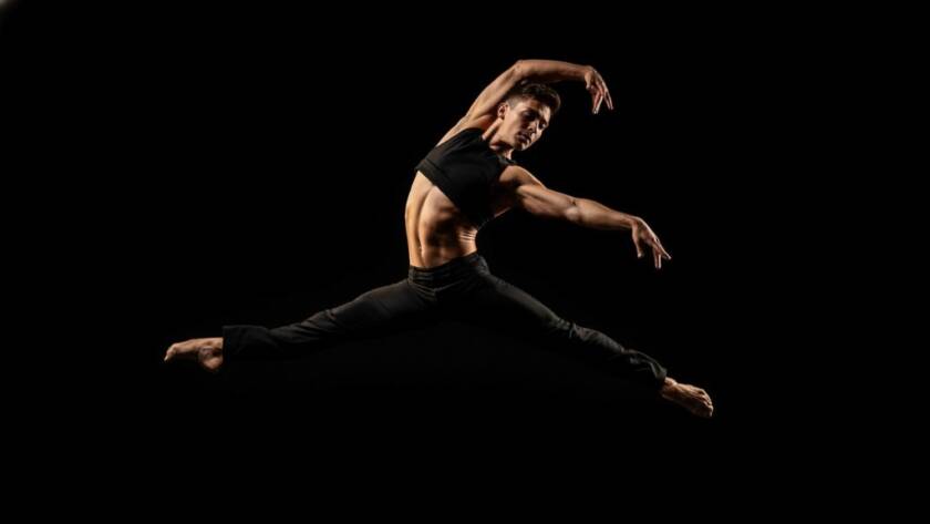 A breathtaking photograph of a ballet dancer mid-air, bathed in dramatic stage lighting, performing an elegant leap in a Vermont South studio, embodying dynamic dance photography Vermont South studios.