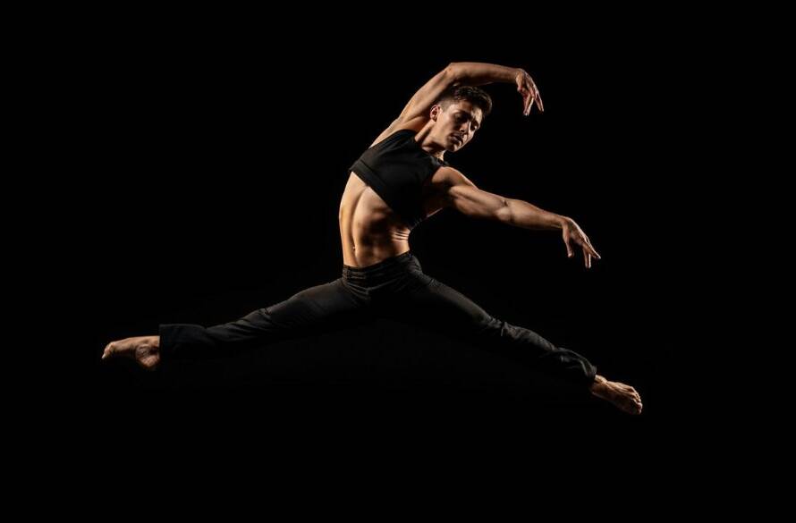 A breathtaking photograph of a ballet dancer mid-air, bathed in dramatic stage lighting, performing an elegant leap in a Vermont South studio, embodying dynamic dance photography Vermont South studios.