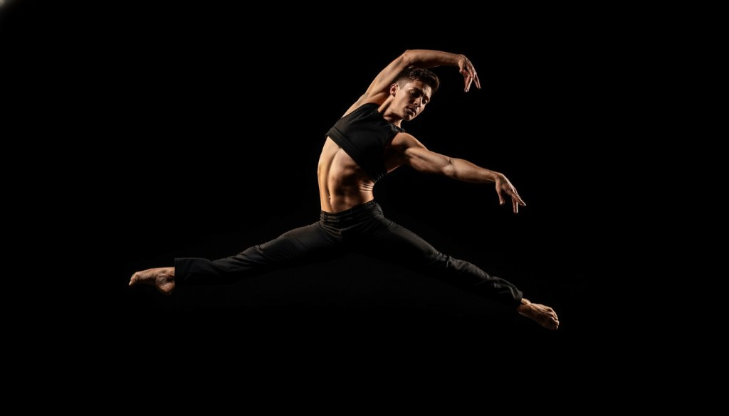 A breathtaking photograph of a ballet dancer mid-air, bathed in dramatic stage lighting, performing an elegant leap in a Vermont South studio, embodying dynamic dance photography Vermont South studios.