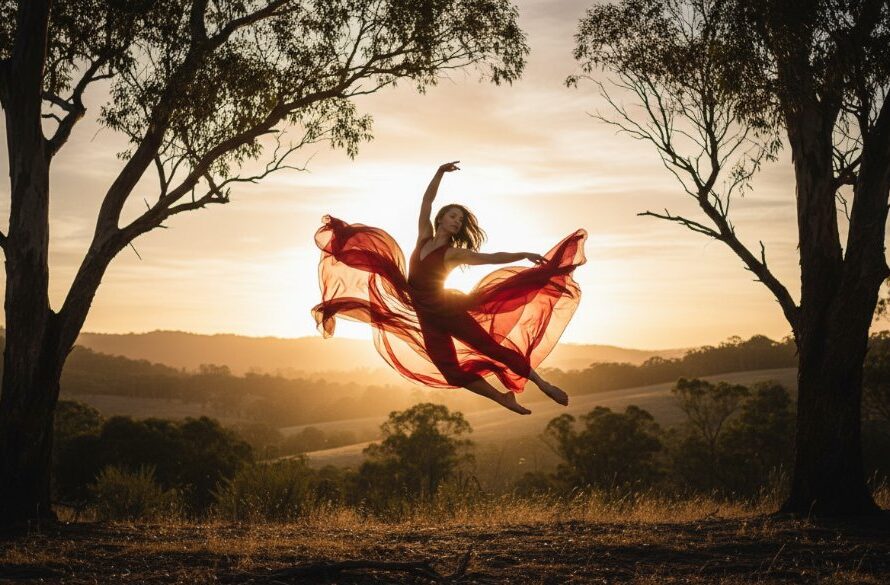 A professional photograph showcasing a dancer in an epic moment, mid-leap with flowing fabric, silhouetted against a dramatic sunset over the Woodend landscape, perfectly illustrating dynamic dance photography Woodend Victoria.