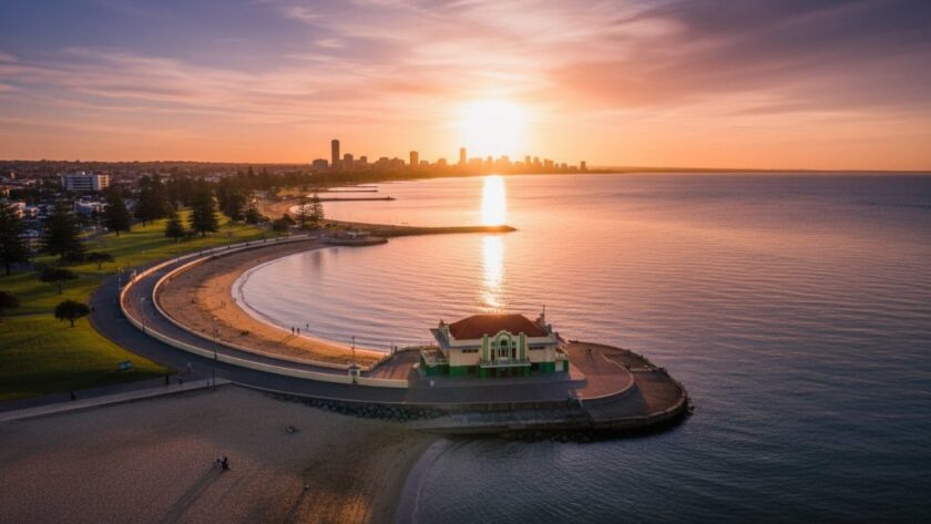 A breathtaking aerial shot of the Eastern Beach promenade and waterfront in East Geelong, captured by drone photography, showcasing golden hour light illuminating the iconic art deco bathing pavilion and vibrant foreshore activity, a truly stunning local vista.